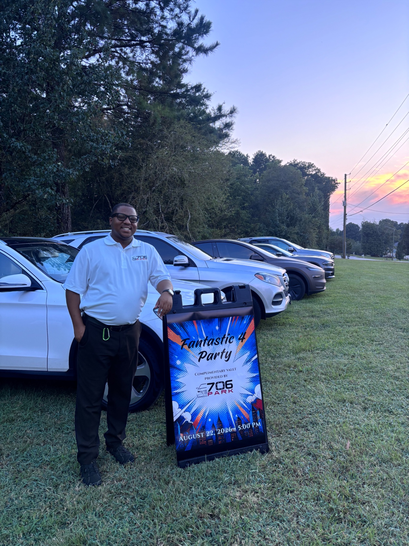 706 Parking Management attendant beside a private party valet sign with rows of parked SUVs at sunset