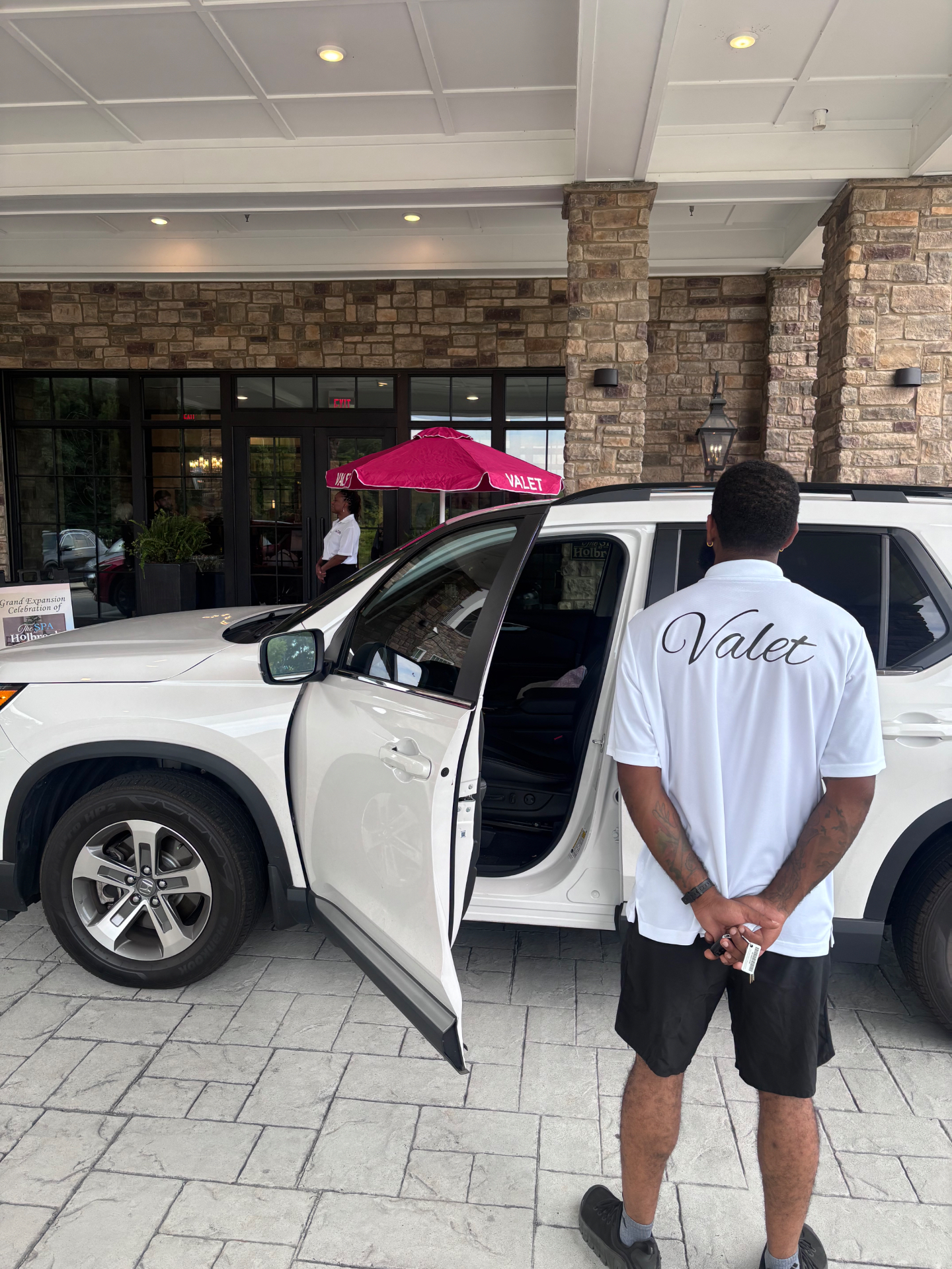 706 Park valet in a white Valet polo holding keys beside a white SUV with the door open at The Spa at Holbrook