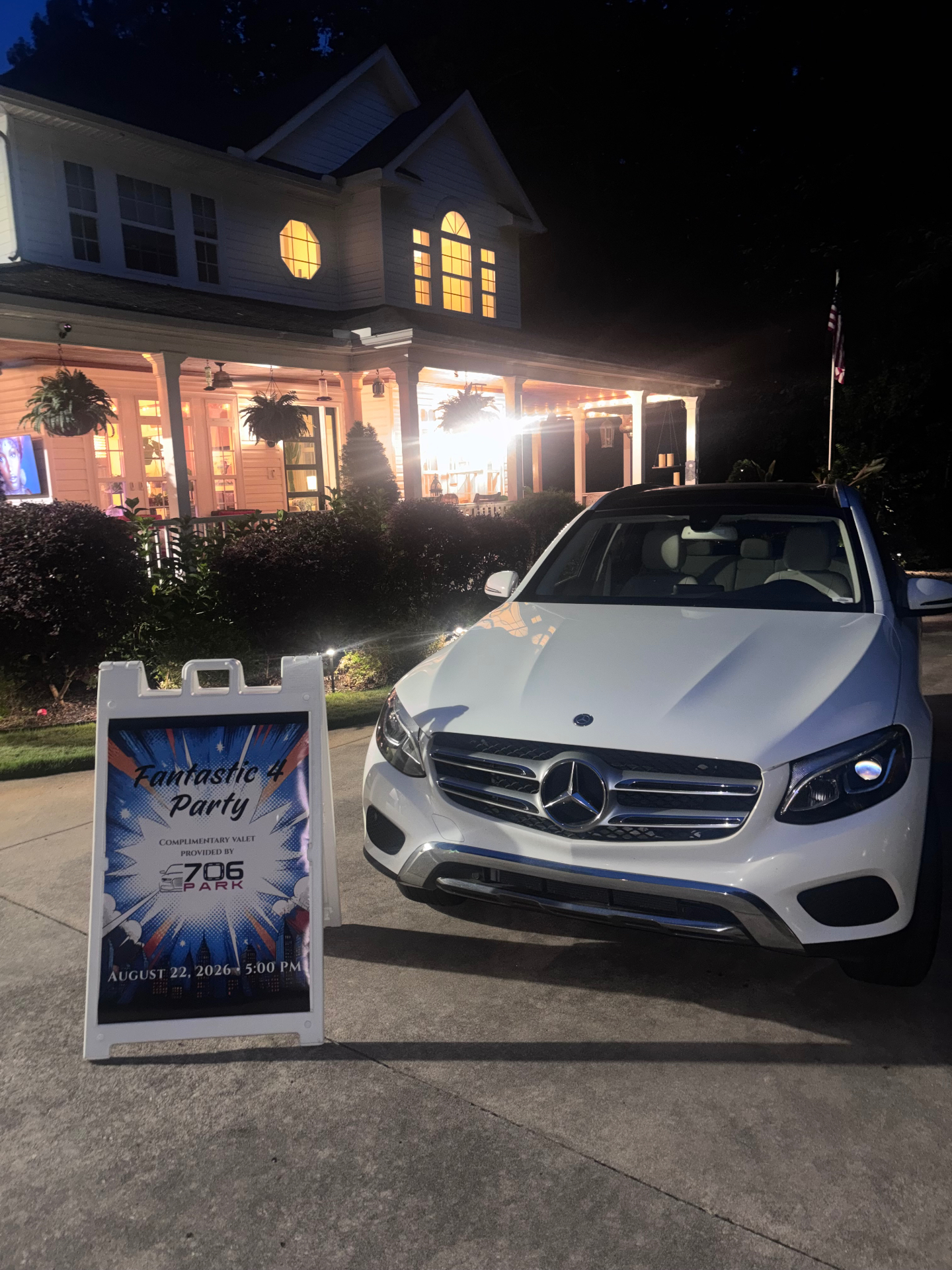 White Mercedes-Benz SUV parked at night in the driveway of a lit home beside a Fantastic 4 Party complimentary valet sign