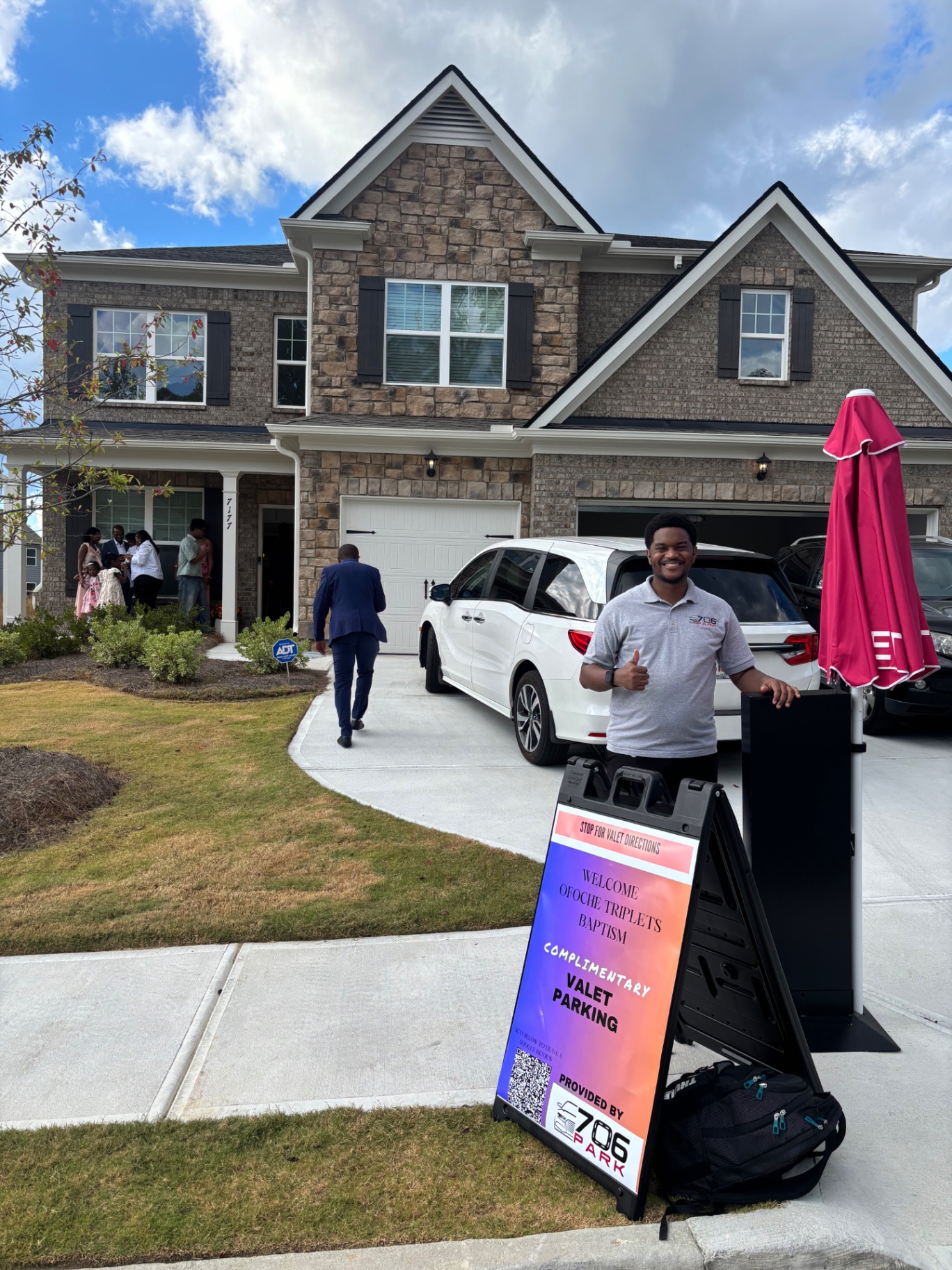 706 Park valet attendant with a complimentary valet parking sign in the driveway of a suburban Atlanta home during a baptism celebration