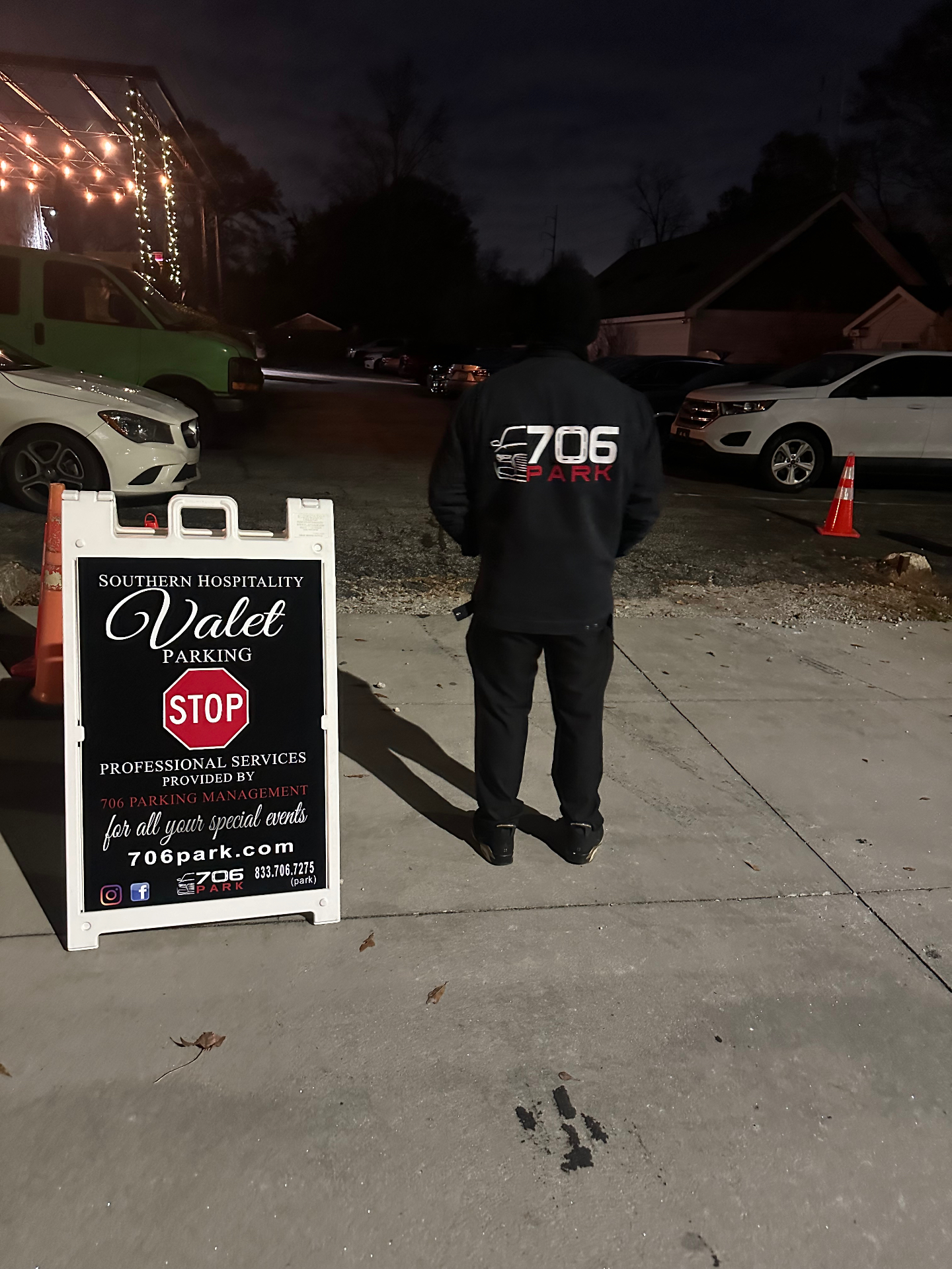 706 Park attendant in a branded jacket directing cars beside a Southern Hospitality Valet Parking sign at night
